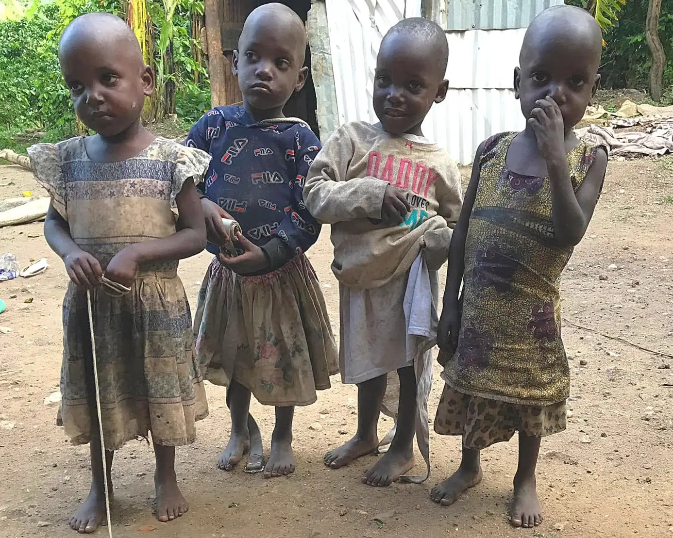 Four children standing together outside their village home