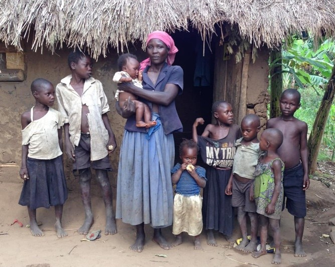 A family with their children in front of their thatched-roof home